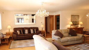 Ein Wohnzimmer mit zwei Sofas, einer Chandelüster, einem Spiegel und einem Gemälde an der Wand.