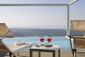 An infinity pool with a view of the landscape, two lounge chairs, a table with a towel and glasses, and two glasses of red wine. - Villa Afrodite for groups:infinity pool,tennis court,bbq,wi-fi and amazing views (Ragusa)