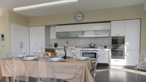 Eine moderne Küche mit weißen Schränken, einer Mikrowelle, einem Backofen und einer Essecke mit Tisch für vier Personen.