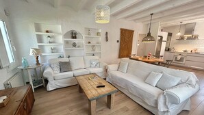 Een moderne woonkamer met een witte bank, een houten salontafel en een keuken op de achtergrond.