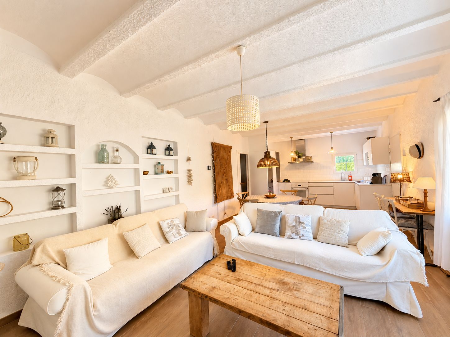 Ein gemütliches Wohnzimmer mit zwei Sofas, einem Holztisch und einer Küche im Hintergrund.