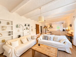 A cozy living room with two sofas, a wooden coffee table, and a kitchen in the background.