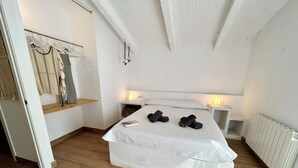 Een slaapkamer met een bed, twee nachtkastjes, een plank en een radiator.