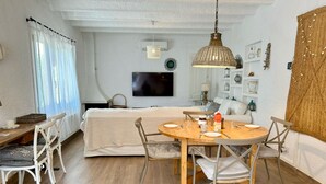 Een gezellige kamer met een bed, een eettafel gedekt voor twee personen, een televisie en een plank met decoratieve spullen.