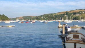 A marina with various boats docked, calm water, and a hilly landscape in the background. - Apartment set in stunning grounds with coastal views & access to coastal paths (Thurlestone)