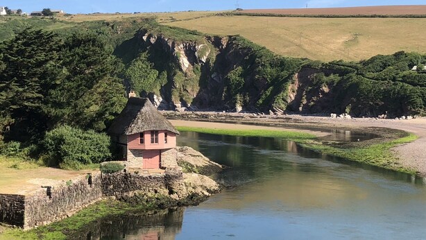 A river with a small pink house on a stone wall by the water. - Apartment set in stunning grounds with coastal views & access to coastal paths (Thurlestone)