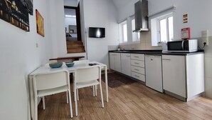 Una cocina moderna con armarios blancos, un microondas y un comedor con mesa y sillas.