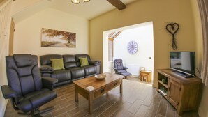 Ein Wohnzimmer mit einer Couch, zwei Sesseln, einem Couchtisch und einem Fernseher-Möbel.