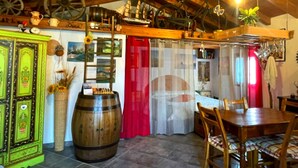 Un comedor rústico con muebles de madera, un barril grande y una cortina roja.