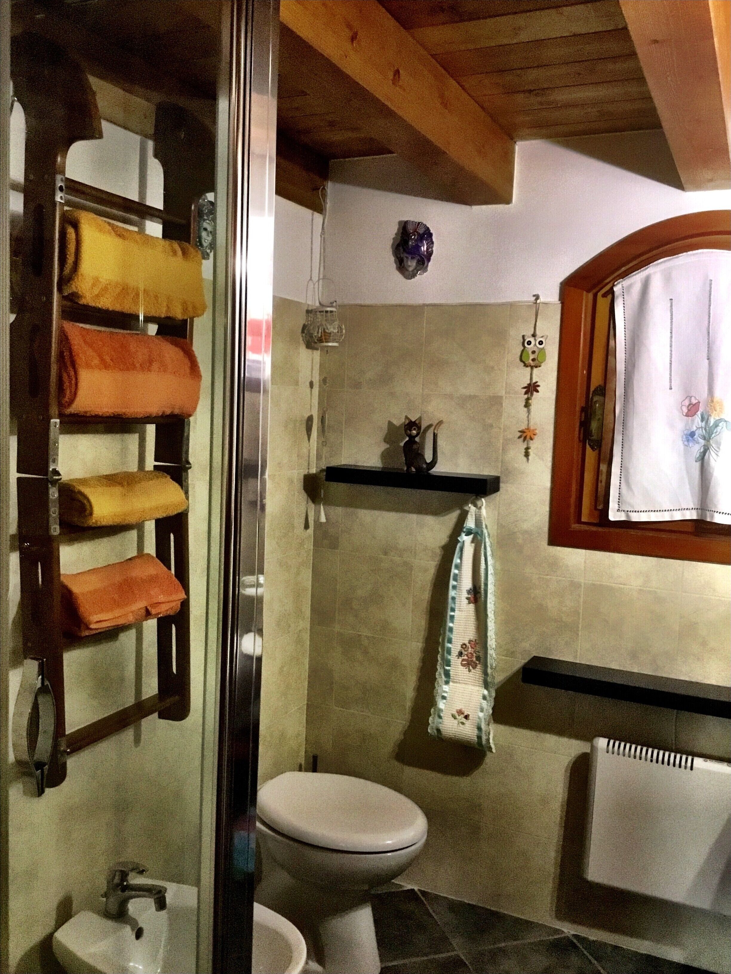 A bathroom with a toilet, sink, and a towel rack with towels.