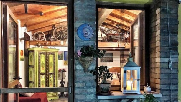 Un interior acogedor con techo de madera, un armario verde, un farol y una planta en maceta sobre una estantería.
