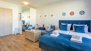 Et moderne soveværelse med en stor seng, en sofa og et lille bord. Væggene er dekoreret, og en dør er synlig.