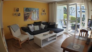 Un salon avec un canapé, un fauteuil, une table basse et un tableau accroché au mur.