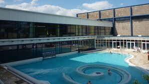 Un bâtiment moderne doté d’un grand espace piscine, comprenant un jacuzzi et une aire de jeux pour enfants.