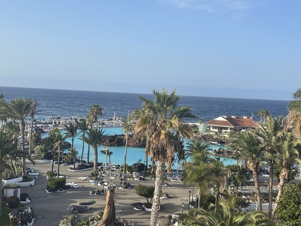 Ein Resort mit Poolbereich, Palmen und Blick auf den Ozean.