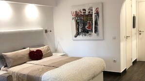 Ein modernes Schlafzimmer mit einem großen Bett, einem Kopfteil, einem Wandbild und einem dunklen Holzboden.