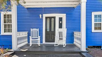 A porch with two rocking chairs and a door.