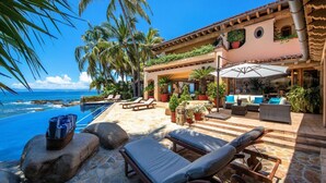 A poolside area with lounge chairs, a pool, and a view of the ocean. - Gated Beachfront luxury Villa fully staffed for the vacation of your dreams (Puerto Vallarta)