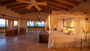 A spacious bedroom with a canopy bed, a view of the ocean, and a patio area with a bench and table. - Gated Beachfront luxury Villa fully staffed for the vacation of your dreams (Puerto Vallarta)