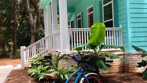 Una bicicleta azul estacionada frente a una casa turquesa con un porche.