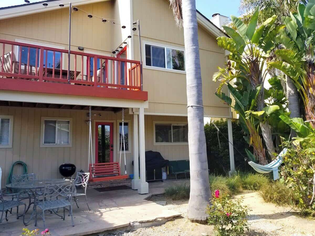 A two-story building with a red balcony, outdoor seating, and a hammock.