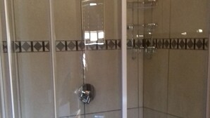 A glass-enclosed shower with a tiled floor and a metal showerhead.