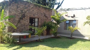 A small brick house with a garden, a table, and potted plants.