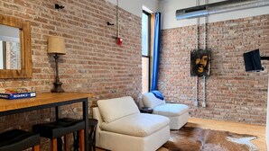 A cozy living room with a brick wall, a wooden table, a sofa, and a cowhide rug. - Downtown Music City Loft living! ~Steps to the Ryman and Broadway (Nashville)