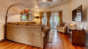Ein großzügiges Wohnzimmer mit einer großen Couch, einem Holztisch und einem Deckenventilator.