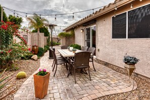 Une terrasse avec une table et des chaises, entourée de plantes en pot et d’un cactus.