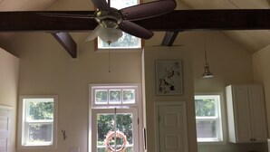 Una cocina con ventilador de techo, una puerta decorada con un adorno festivo, y una ventana con vistas a la vegetación.