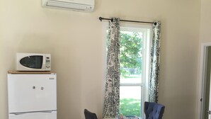 Un comedor con una mesa dispuesta para dos, un refrigerador blanco y un microondas encima.