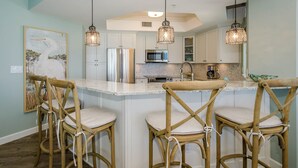 A kitchen with a central island, bar stools, stainless steel appliances, and pendant lighting. - FIRST WEEK OF AUGUST JUST OPENED! (Destin)