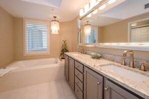 A modern bathroom with a large bathtub, two sinks, and a vanity with drawers. - FIRST WEEK OF AUGUST JUST OPENED! (Destin)