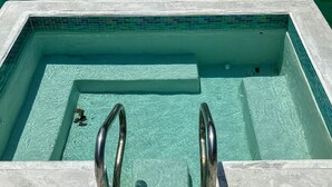 Una piscina rectangular con agua cristalina, bordes con mosaicos y barandillas de metal.