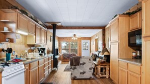 Una cocina amplia con armarios de madera, estufa y comedor con mesa y sillas.
