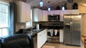 Une cuisine moderne avec des armoires blanches, des appareils en acier inoxydable et un fauteuil en cuir noir.