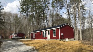 Une cabane rouge avec une allée en gravier et une voiture garée à proximité.