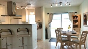 A modern kitchen with a central island, bar stools, and a dining area with a round table and chairs. - Private Heated  Pool House 6 miles from the Beach (Bradenton)