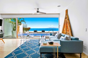A modern living room with a pool view, a ceiling fan, and a large window. - Spectacular Sayan Oceanfront Penthouse with Sparkling New Rooftop Private Pool (Puerto Vallarta)