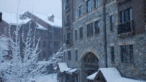 Ein Gebäude aus Stein mit zahlreichen Fenstern und einem mit Schnee bedeckten Dach.