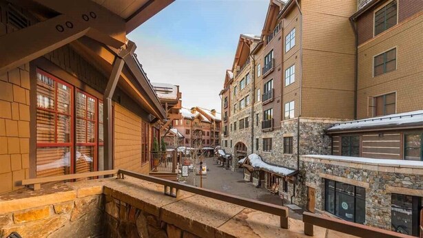 Ein gemütlicher Innenhof mit Steinmauern, hölzernen Bänken und Blick auf traditionelle Gebäude mit Balkonen.
