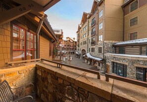 A cozy courtyard with stone walls, wooden benches, and a view of traditional buildings with balconies. - One Bedroom Condo in the Northstar Village (Truckee)