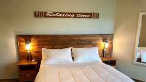 A neatly made bed with a quilted headboard, two bedside lamps, and a wooden sign above stating "Relaxing time". - Paradise At A Great Price, Amazing Renovated Waterfront Escape: Private Balcony! (St. Thomas)