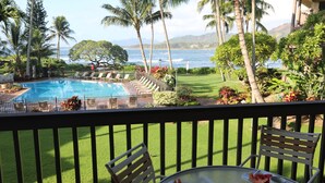 A poolside view with a table, chairs, and a view of the ocean. - Paradise found-Ocean Front 2 Bdr-Bath-Lanais—Primary bedroom faces ocean FULL AC (Kapaa)