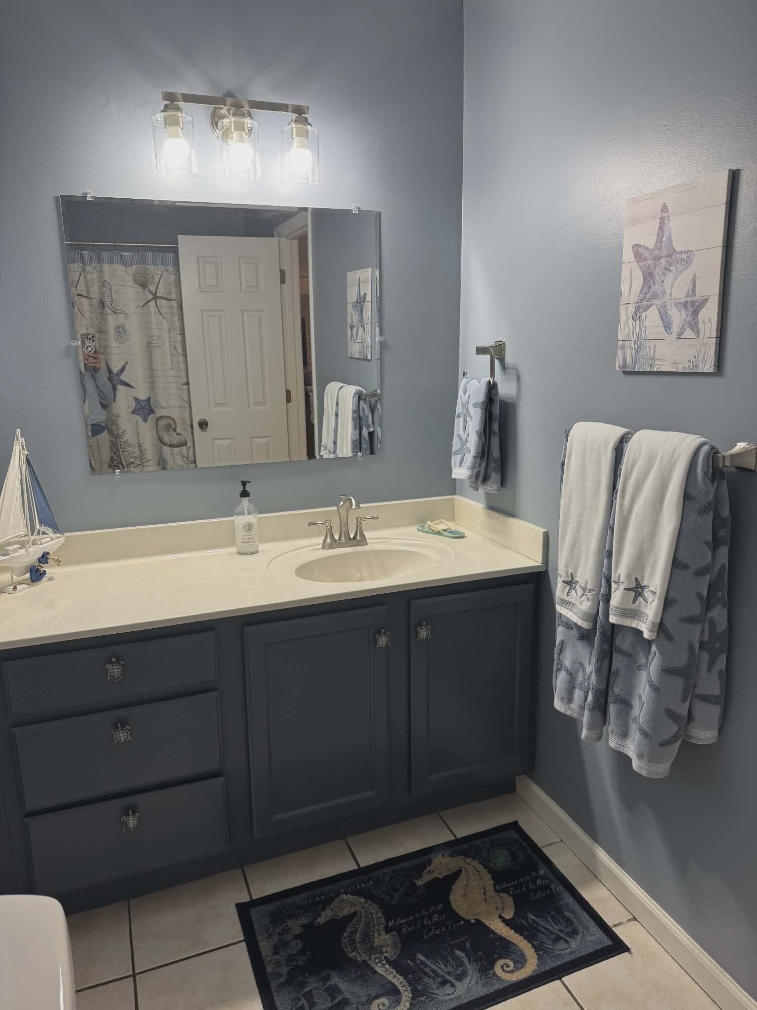 A bathroom with a large mirror, a sink, and a towel rack.