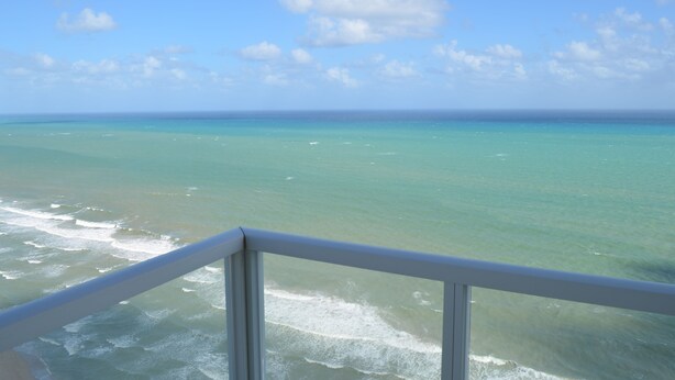 A view of the ocean from a balcony with a railing.