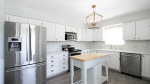Una cocina moderna con armarios blancos, electrodomésticos de acero inoxidable y encimera de madera.