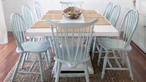 Comedor con una mesa blanca, sillas azul claro y una lámpara colgante.