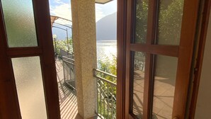 A wooden door leading to a balcony with a view of a lake and mountains. - Outdoor Veranda w Lakefront Views, Lake Access & Swimming Dock (COMO)